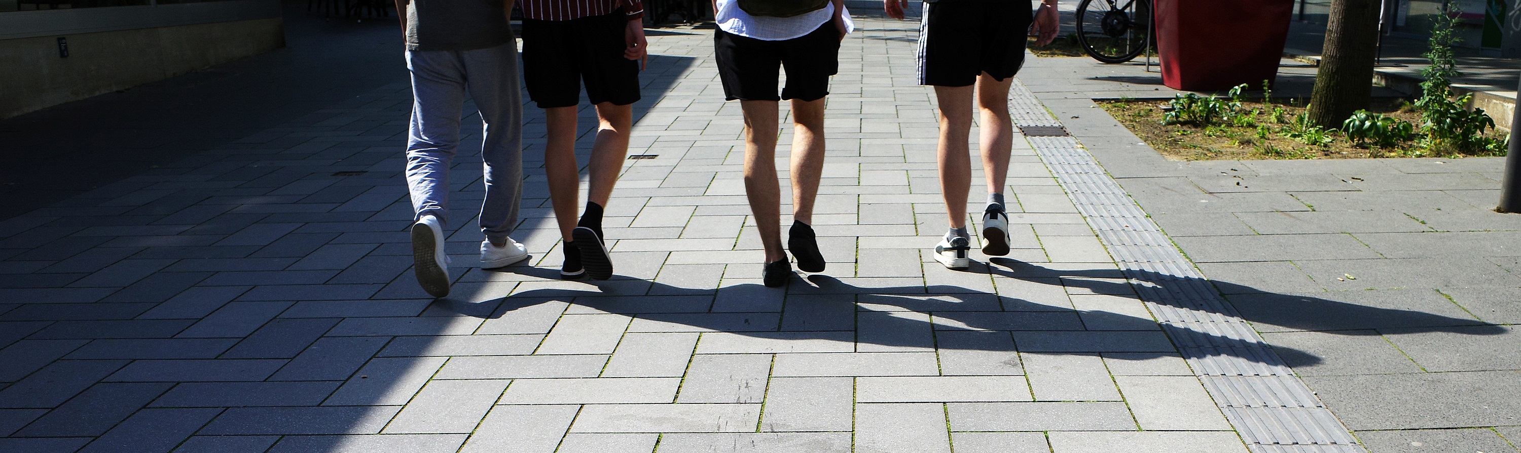 four young people walking away from the camera down a street