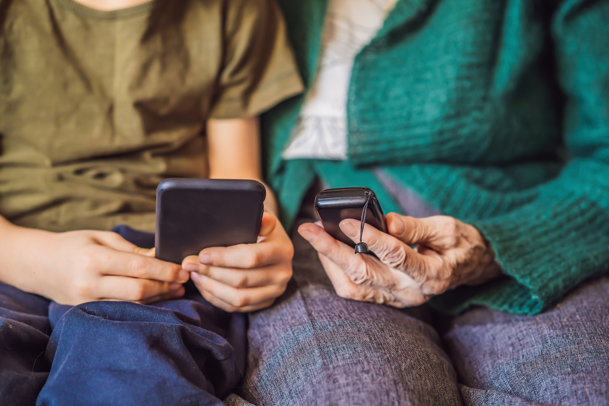 a younger person and an older person sit together holding phones