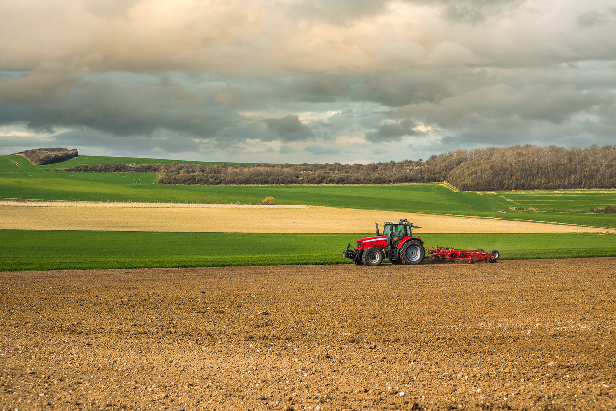 image of tractor pulling plough under cloudy skies