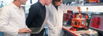 The aiPRINT project team examining lab equipment. 