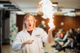 A man in a lab coat doing a science experiment with fire. 